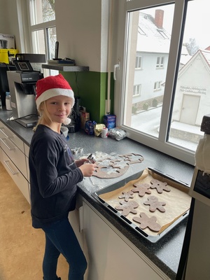 Ein Mädchen mit Weihnachtsmütze backt Plätzchen