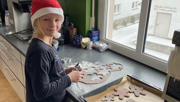 Ein Mädchen mit Weihnachtsmütze backt Plätzchen