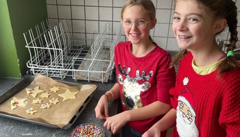 Zwei Mädchen backen Plätzchen und lächeln in die Kamera