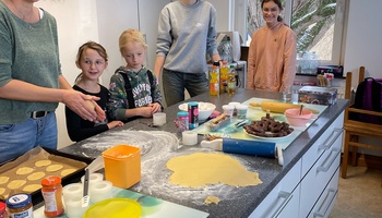 vier Kinder und eine Frau backen Plätzchen
